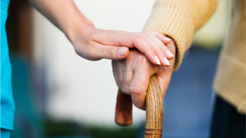 Elderly man with cane walking with nurse