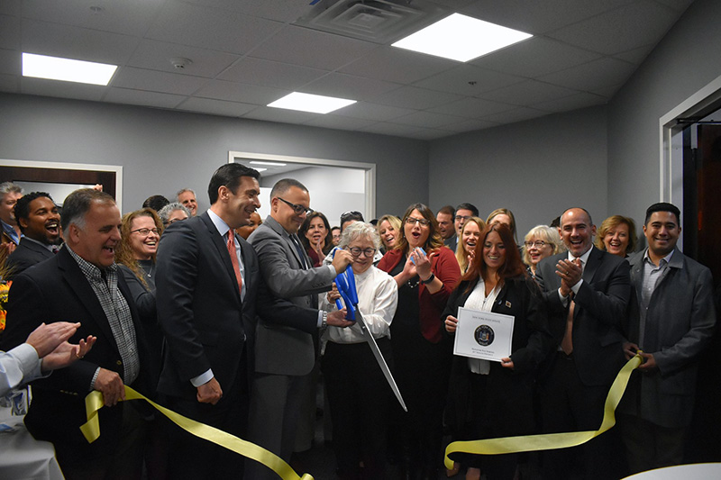 jennifer van tuyl and anthony morando cutting ribbon revealing new office space